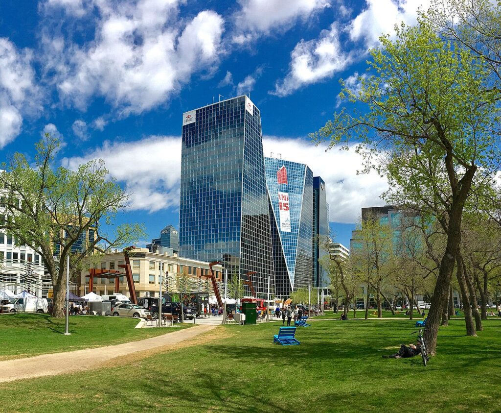 Hautes tours du centre-ville aux extérieurs en verre bleu, encadrées par un parc municipal à Regina, en Saskatchewan.